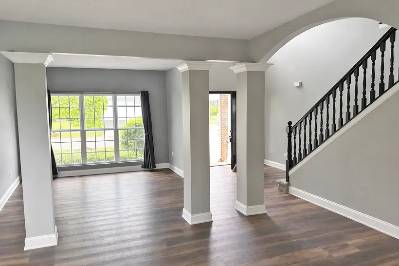 Open living area with smooth painted walls, white trim, and columns